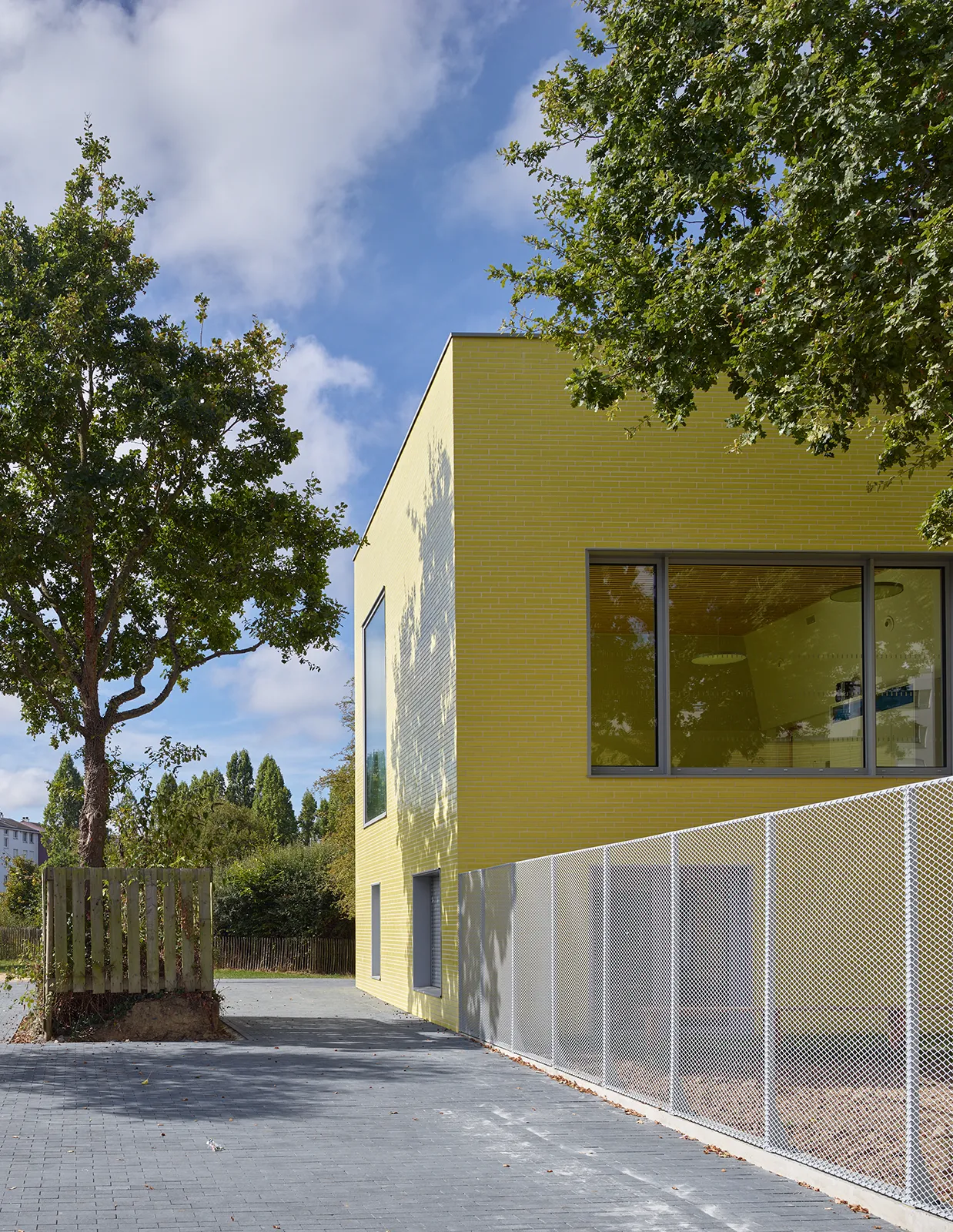 Vue sur la rue de la Pilate du patio et du volume de l’école maternelle et accueil périscolaire à Saint-Jaques de la Lande