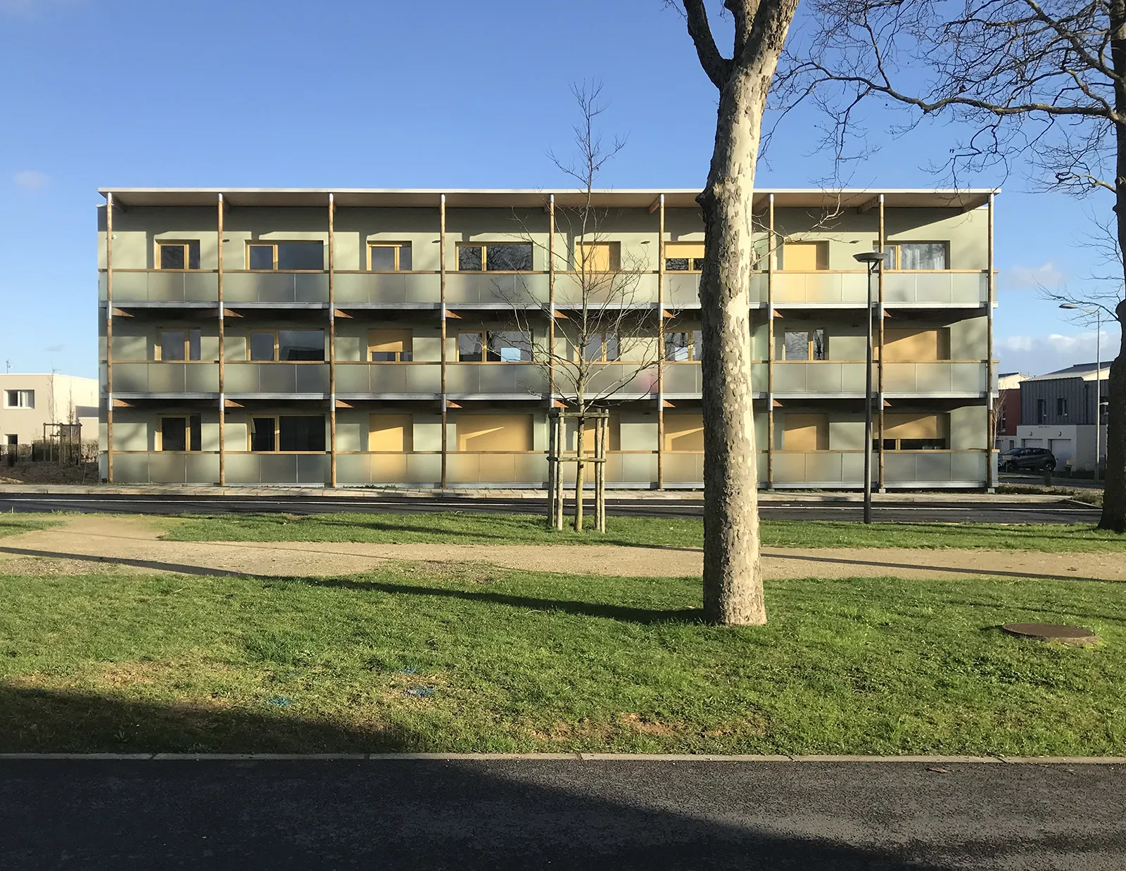 Façade Ouest sur le mail planté d’un bâtiment de logements à coursives à Colombelles