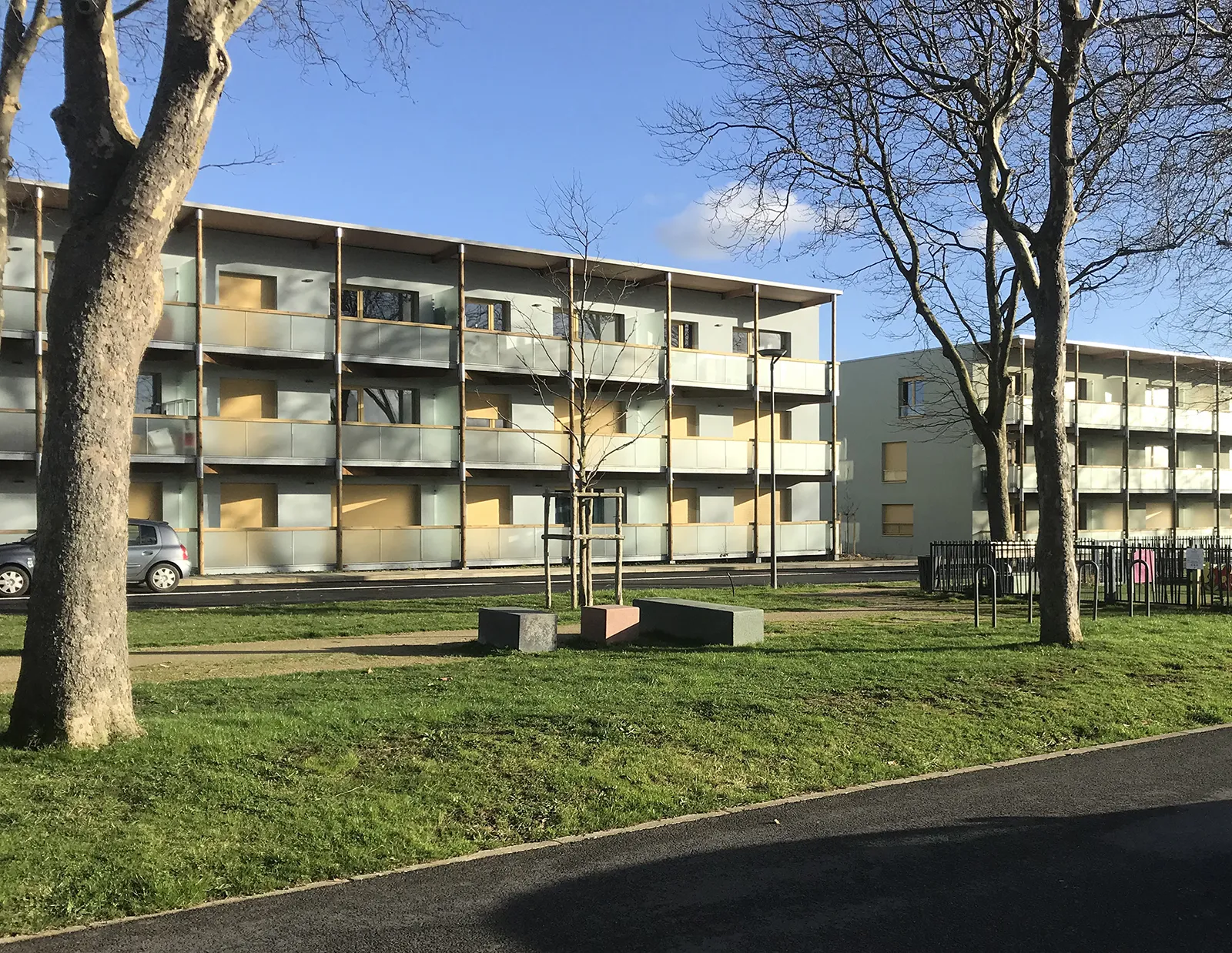 Vue des façades Ouest des logements à coursive à Colombelles depuis le mail planté