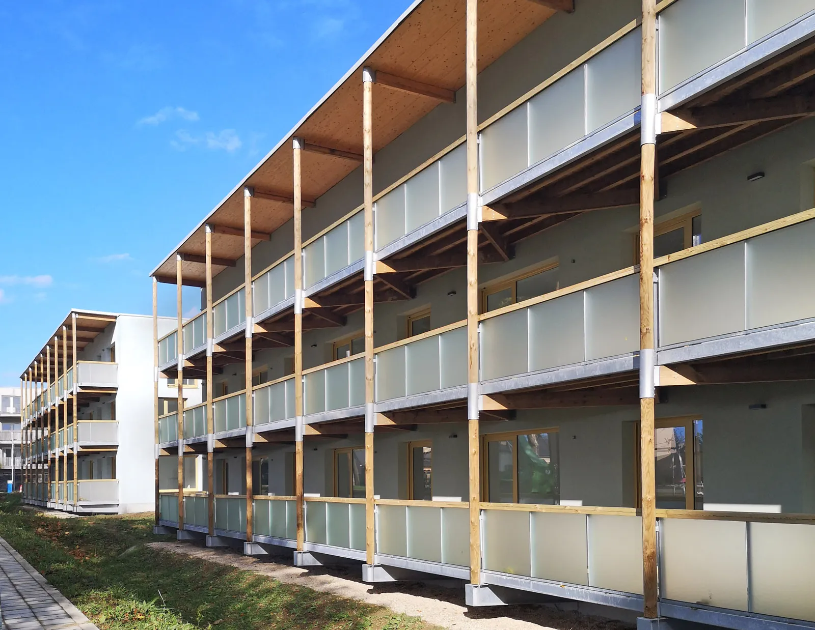 Vue des balcons ossature bois et gardes-corps vitrés sur le mail planté